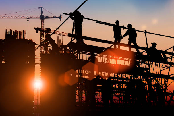 Silhouette Two engineers consult and inspect high-rise construction work over blurred industry background with Light fair.Create from multiple reference images together